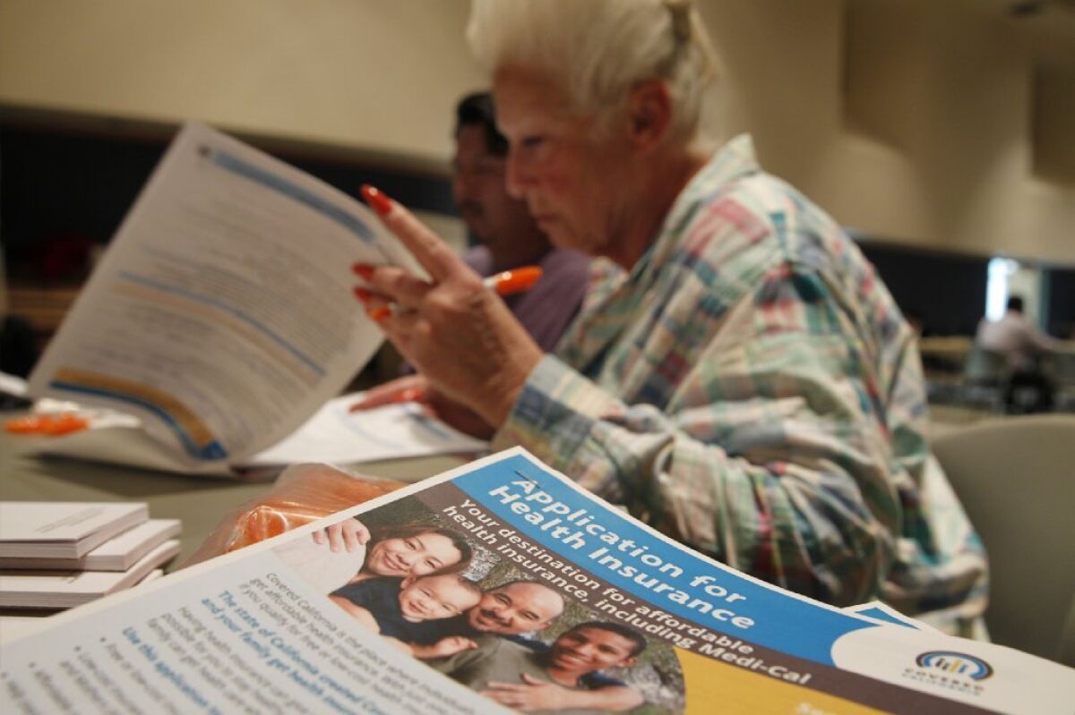 Karyn Jackson helps applicants fill out Covered California health insurance forms at a March enrollment event in Pasadena. Some consumers have hit obstacles after signing up.