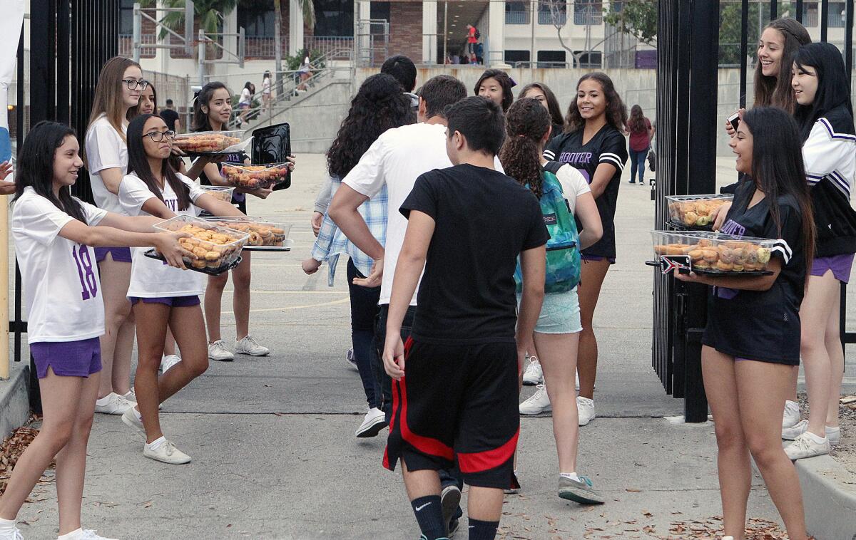 In this Aug. 2015 photo, students greet their peers with free donuts at Hoover High School on the first day of school.