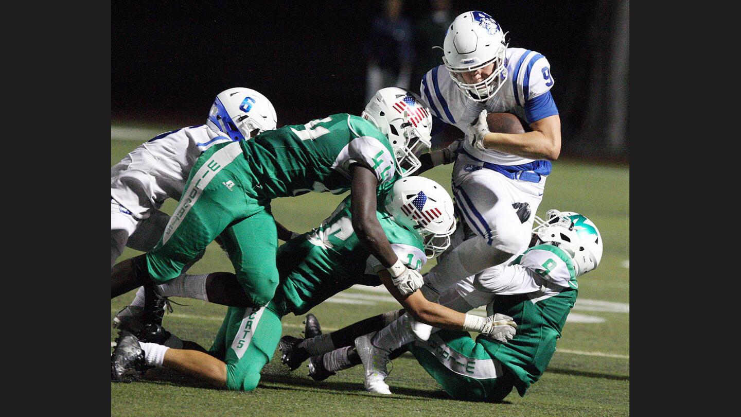 Burbank's Duncan Smith, looking like he's about to be tackled, steps out of the grasp of the Monrovia defenders and runs further down field in the first half of a non-league football game at Monrovia High School on Friday, August 25, 2017.