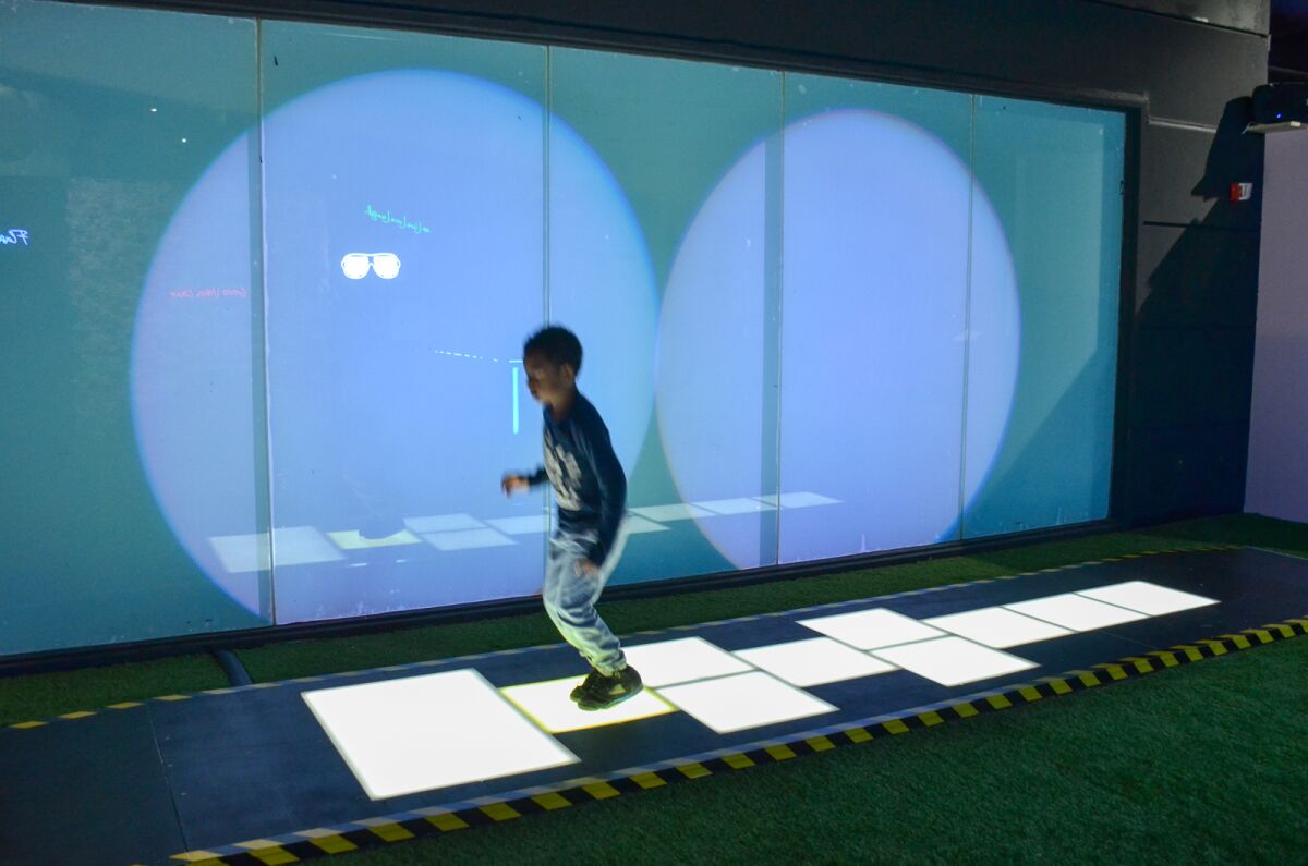 A child hops on an illuminated hopscotch board.