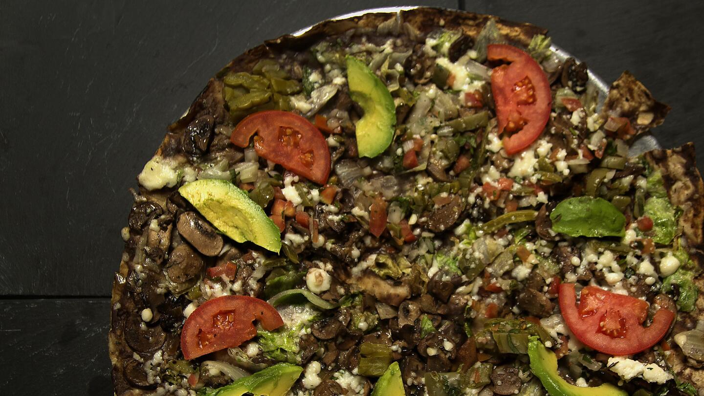 Tlayuda Vegetariana, layered with black bean paste, topped with queso fresco, cabbage, mushrooms, cactus, avocado and tomatoes.