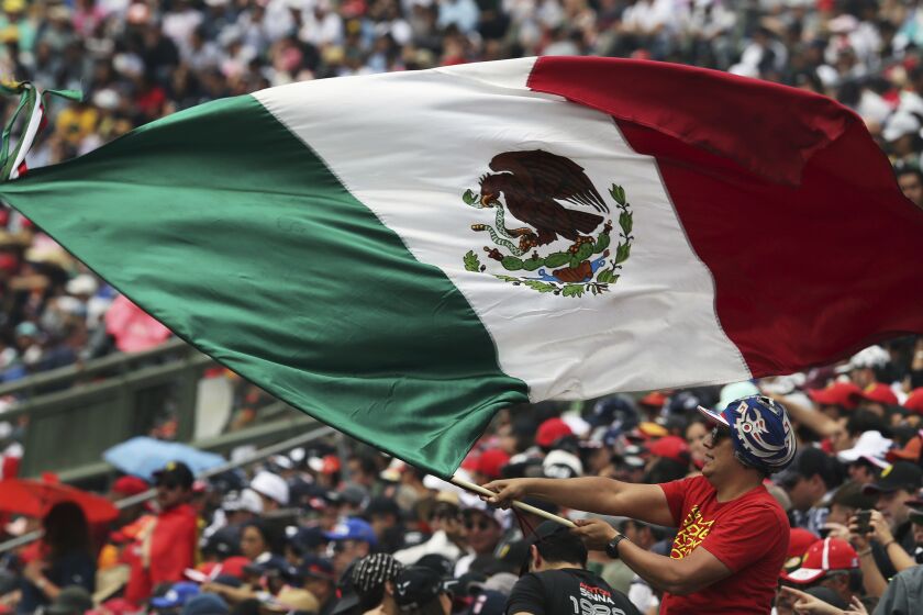 A fan flies a Mexican flag during the qualifying session for the Formula One Mexico Grand Prix auto race at the Hermanos Rodriguez racetrack in Mexico City, Saturday, Oct. 26, 2019. (AP Photo/Marco Ugarte)