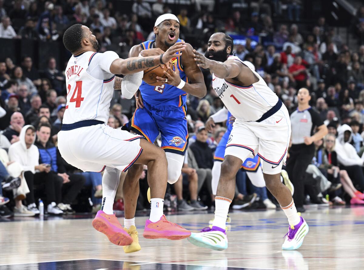 Thunder guard Shai Gilgeous-Alexander, center, is fouled by Clippers guard Norman Powell, left, as James Harden tries to help