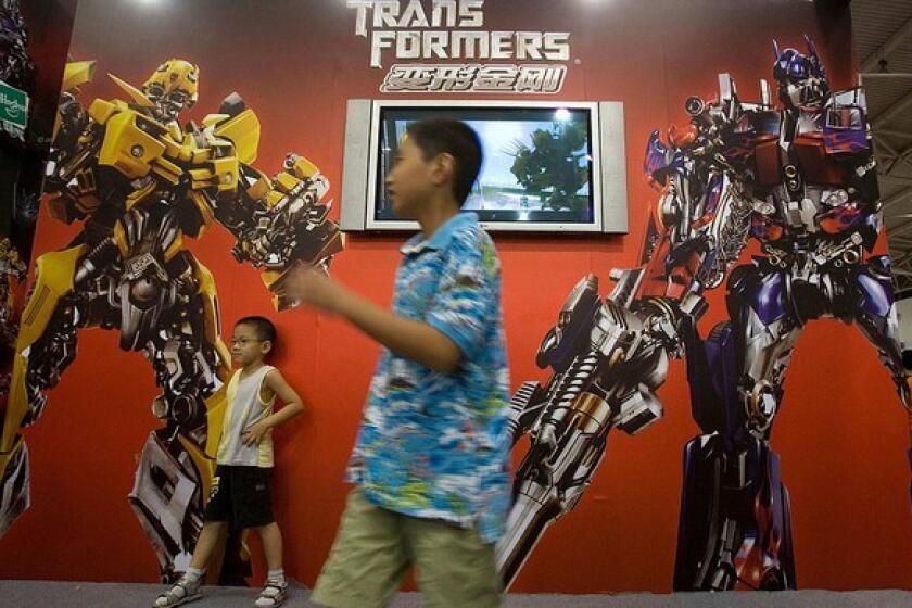 Chinese children pose for photos near an advertisement for the Hollywood movie "Transformers" during an animation fair held in Beijing in July 2007. The latest "Transformers" sequel has sold more than $159 million worth of tickets in China this summer.