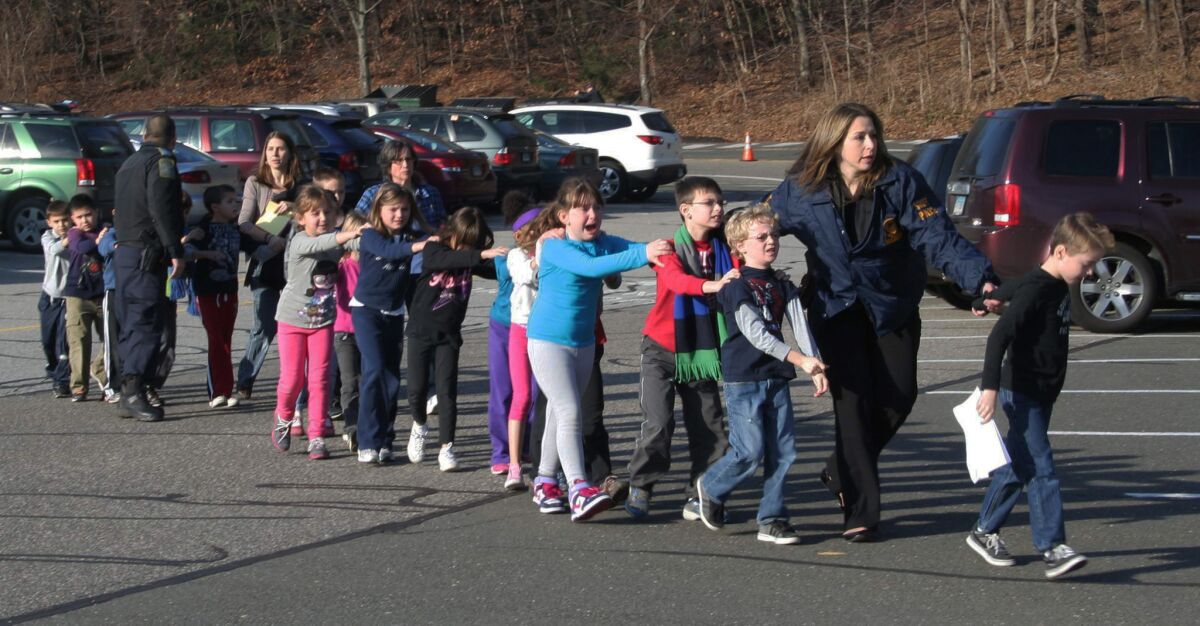 Connecticut State Police lead a line of children from the Sandy Hook Elementary School in Newtown, Conn., after a mass shooting at the school.