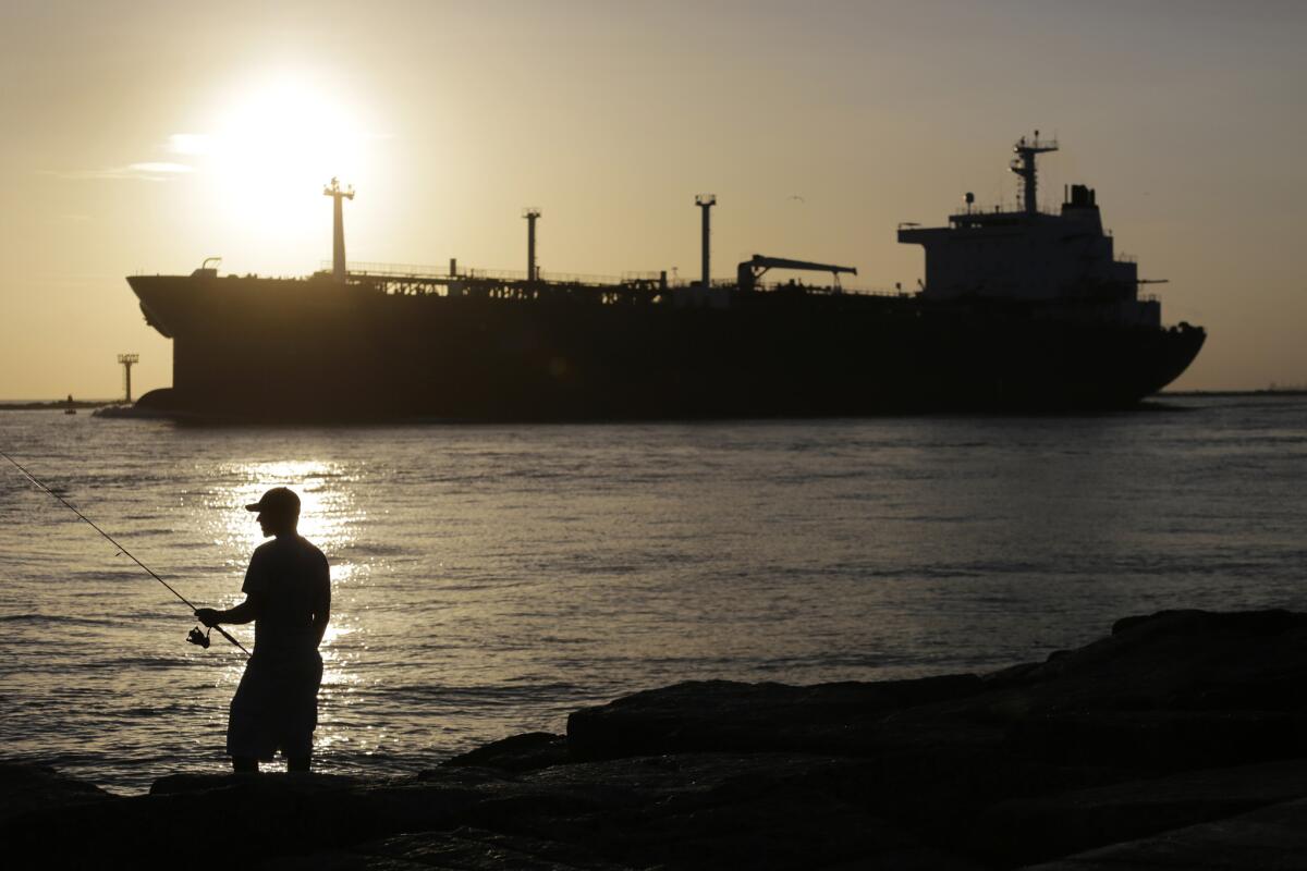 An oil tanker passes a fisherman as it enters a channel near Port Aransas, Texas, on July 21, 2015.