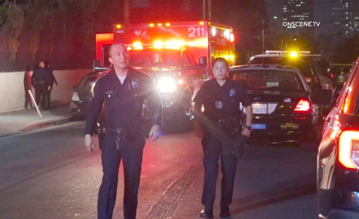 Police officers stand near emergency vehicles.