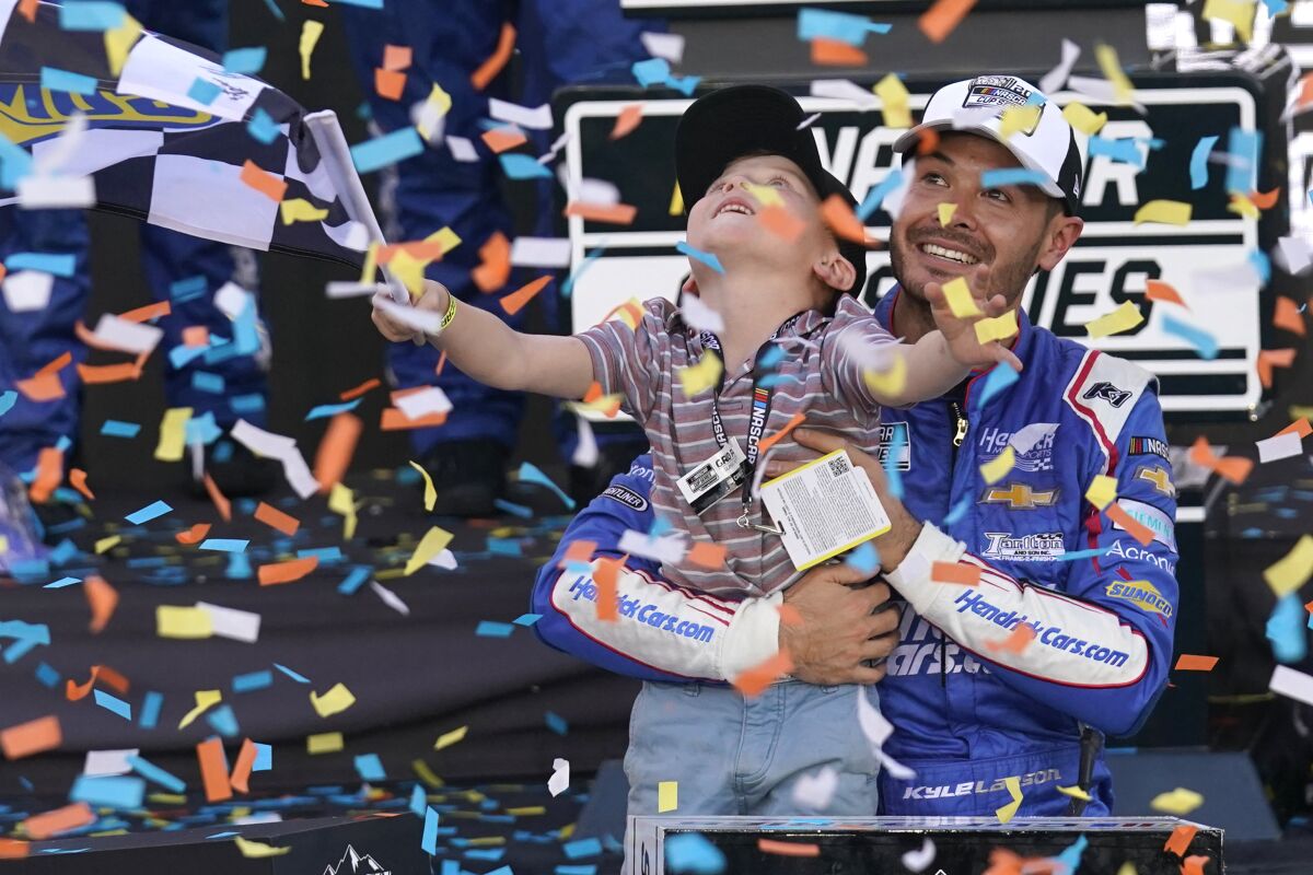 Kyle Larson, right, and his son Owen celebrate after winning a NASCAR Cup Series auto race and championship on Sunday, Nov. 7, 2021, in Avondale, Ariz. (AP Photo/Rick Scuteri)