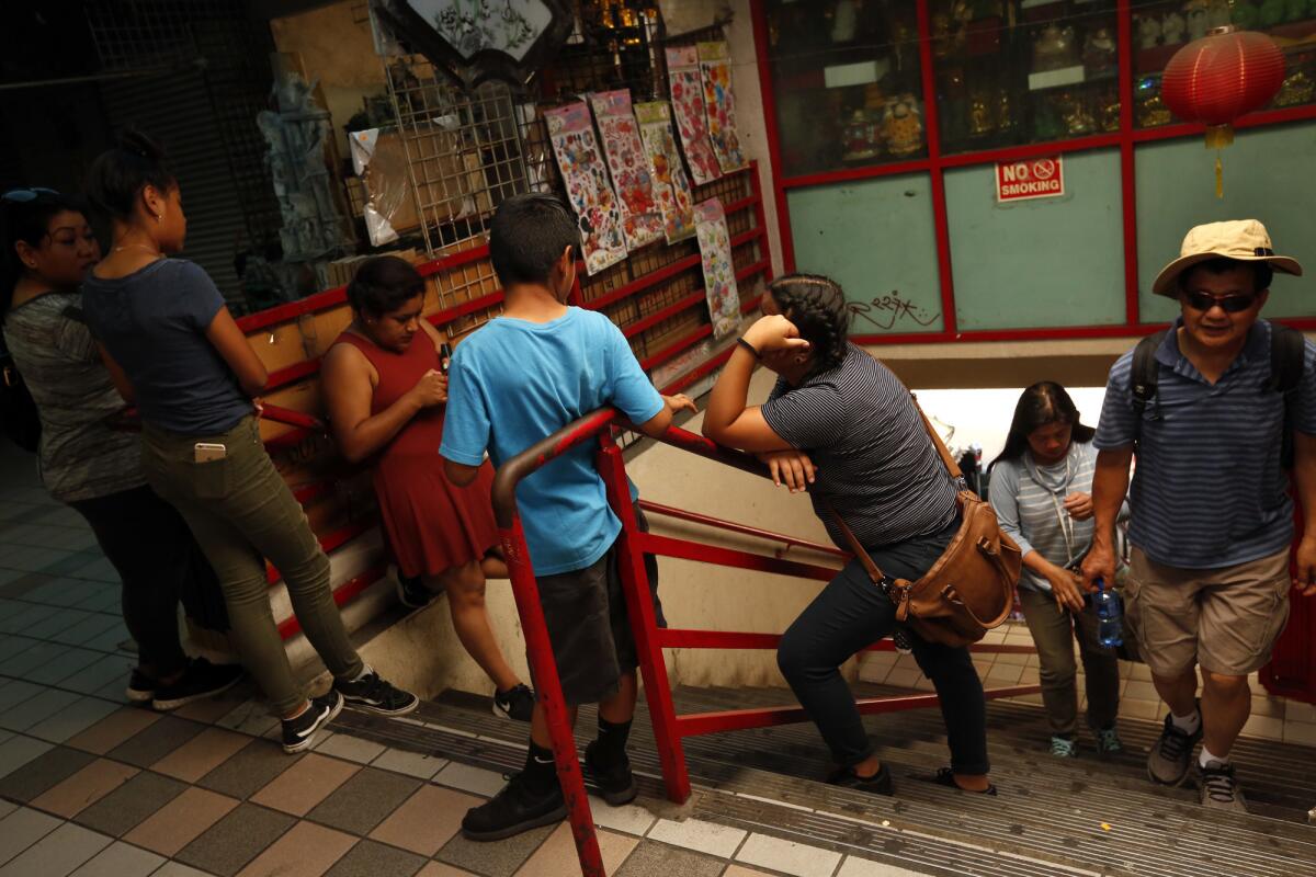 Some shoppers take a break while others arrive at the swap meets in Chinatown. (Genaro Molina / Los Angeles Times)