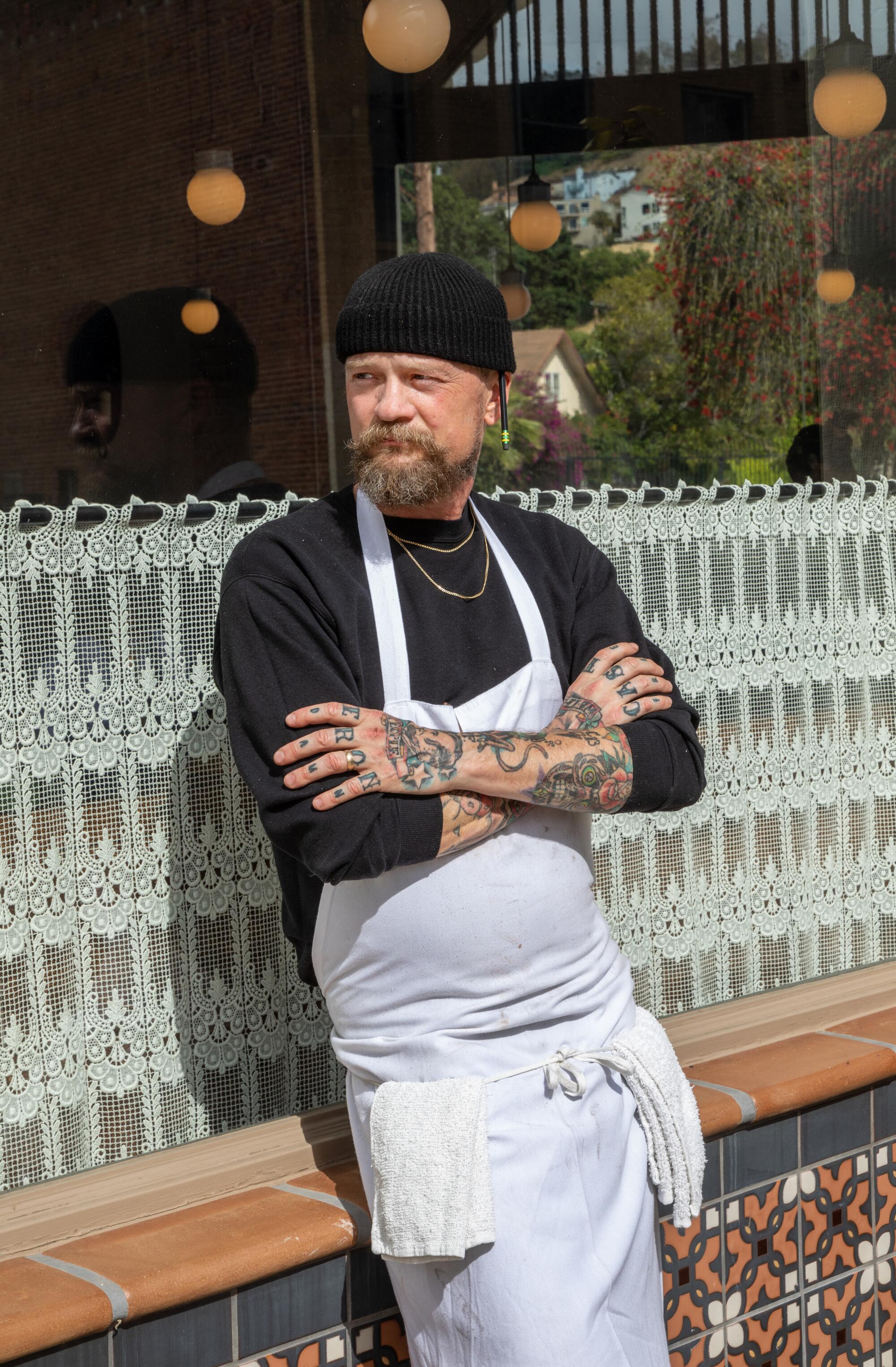 Brian Dunsmoor, in a white apron and black shirt and beanie, outside his restaurant in L.A.