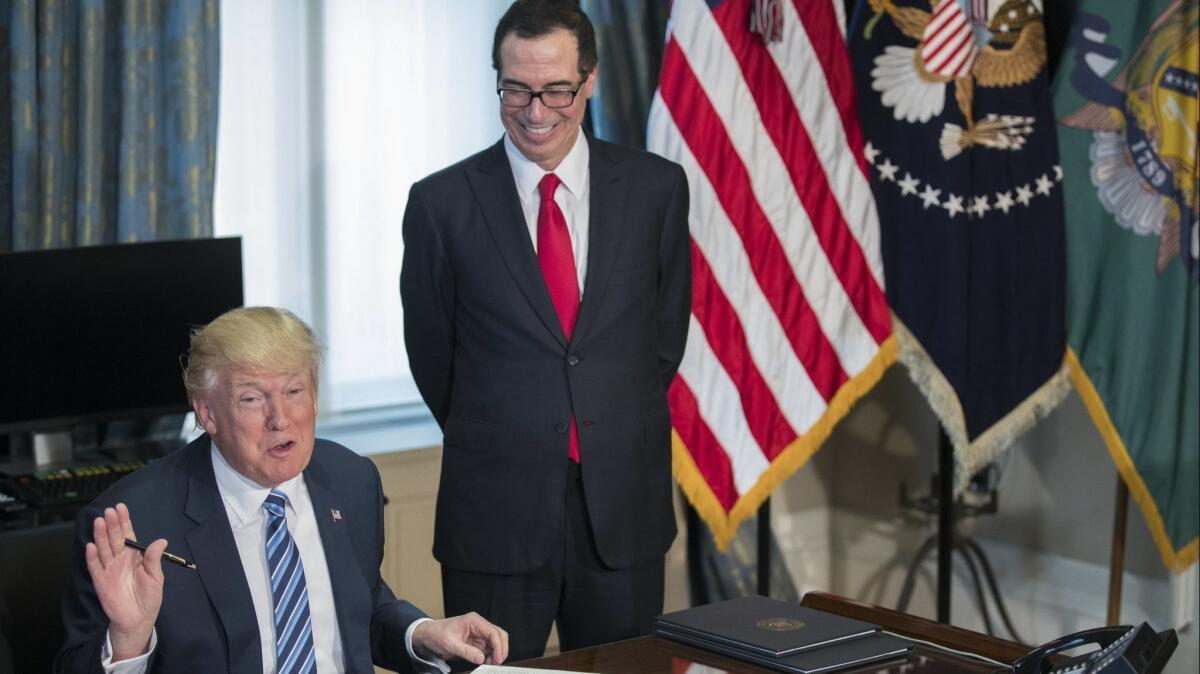 President Trump signs a memo ordering a review of the Dodd-Frank financial regulations in April 2017 as Treasury Secretary Steven T. Mnuchin watches.