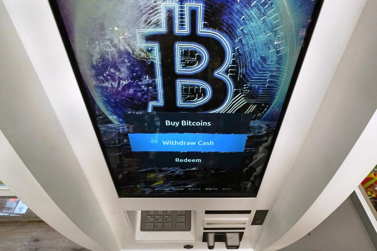 An ATM has a display screen with the words "Buy Bitcoins," "Withdraw Cash" and "Redeem."