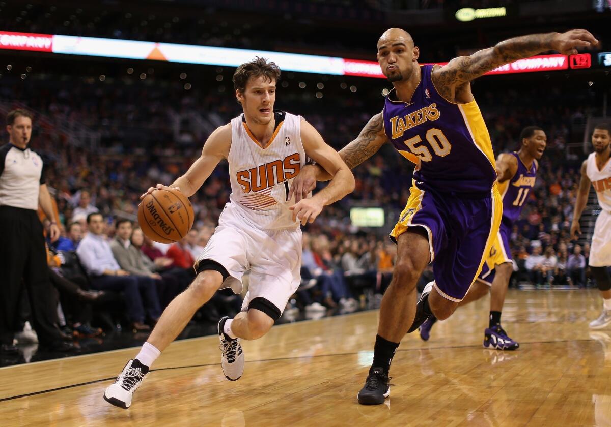 Lakers center Robert Sacre tries to cut off a drive by Suns point guard Goran Dragic.