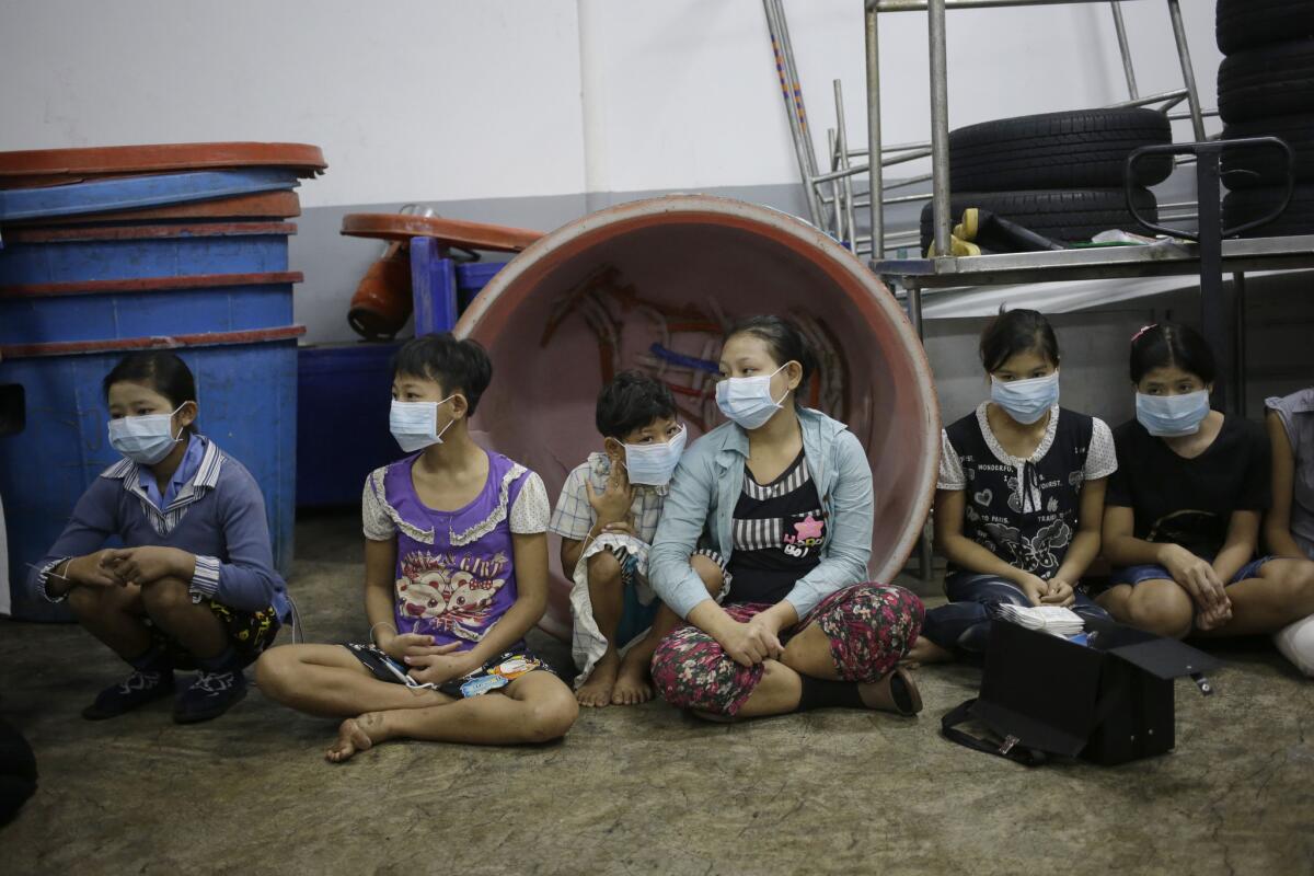 Niños y adolescentes esperan sentado a ser registrados por funcionarios durante un registro en una fábrica de gambas en Samut Sakhon, Tailandia. (Foto AP/Dita Alangkara)