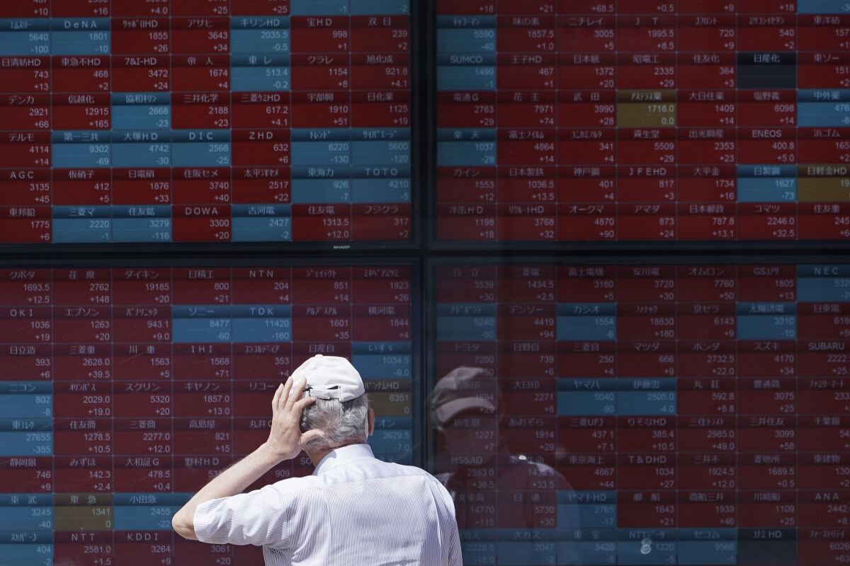A man looks at an electronic stock board showing Japan's Nikkei 225 index at a securities firm in Tokyo Wednesday, Aug. 12, 2020. Shares were mostly lower in Asia on Wednesday after Wall Street pumped the brakes on its recent rally. (AP Photo/Eugene Hoshiko)