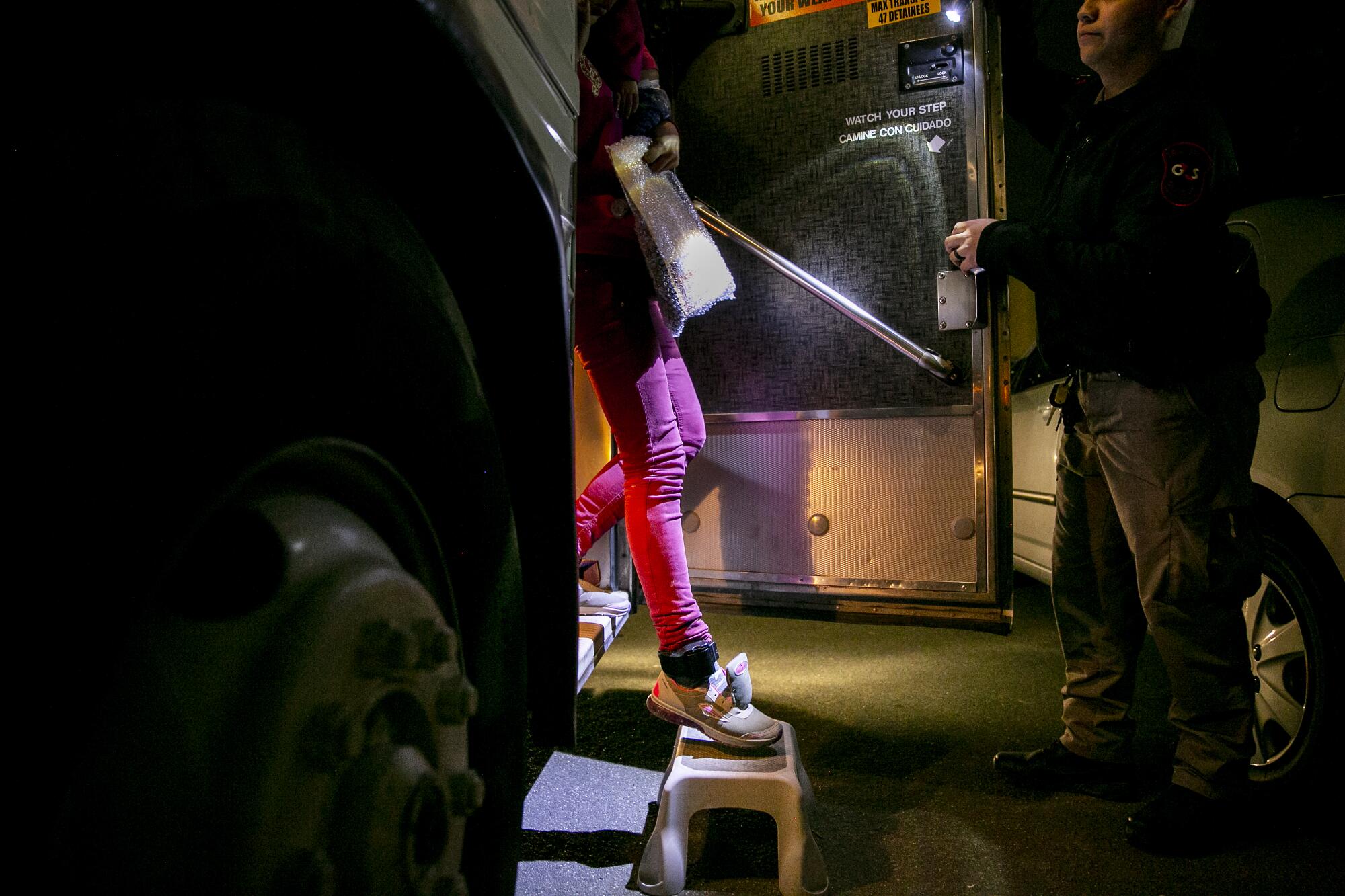 In January 2019, migrants wearing ankle monitors step off a bus at the Rapid Response Network's shelter