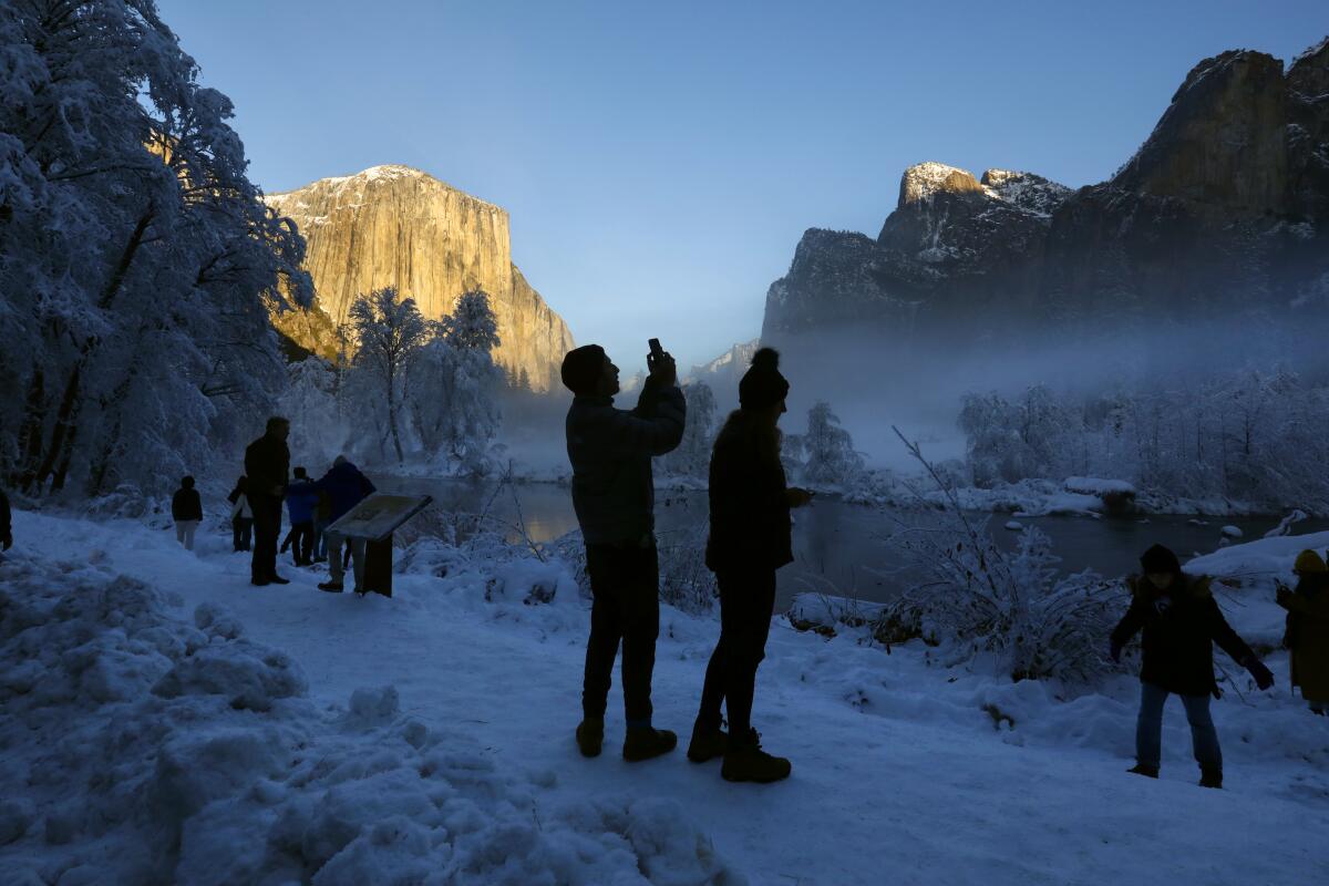 People take pictures in the snow at Yosemite.