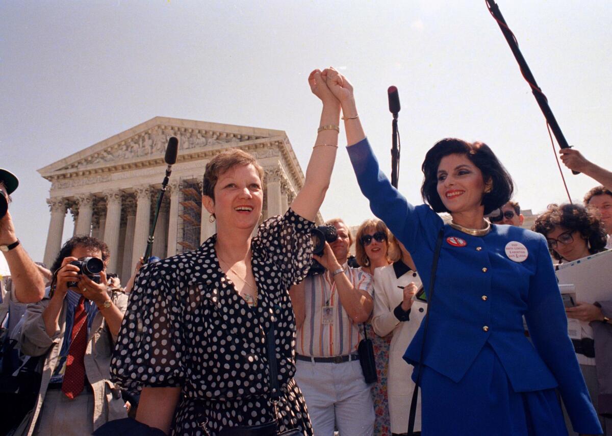 Norma McCorvey, "Jane Roe" in the 1973 court case, left, and her attorney Gloria Allred hold hands as they leave the Supreme Court building in Washington after sitting in while the court listened to arguments in a Missouri abortion case in 1989.