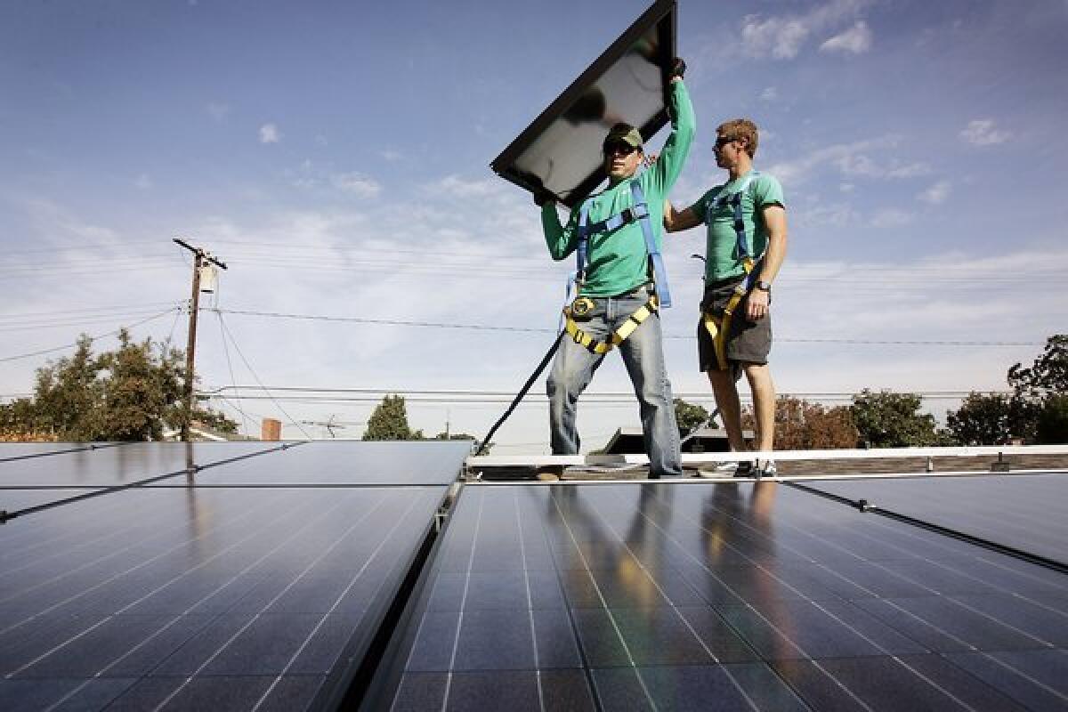 SolarCity workers install solar modules on the roof of a Long Beach home.