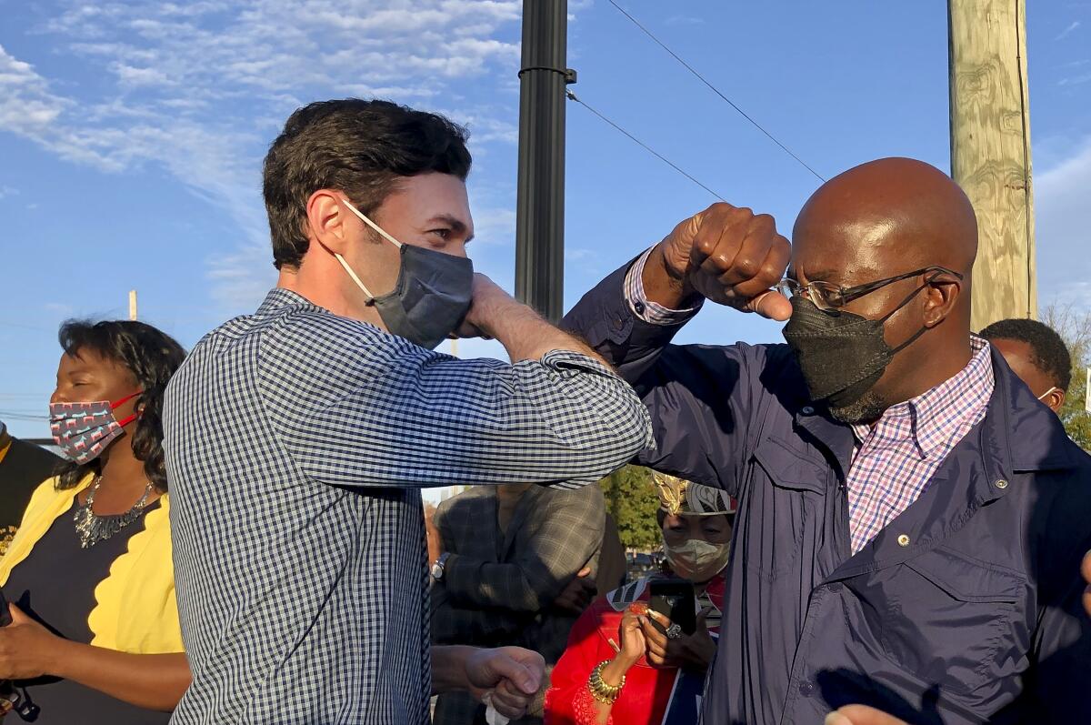 Democrats Jon Ossoff and Raphael Warnock tap elbows during a joint campaign rally on Nov. 15, 2020, in Marietta, Ga.