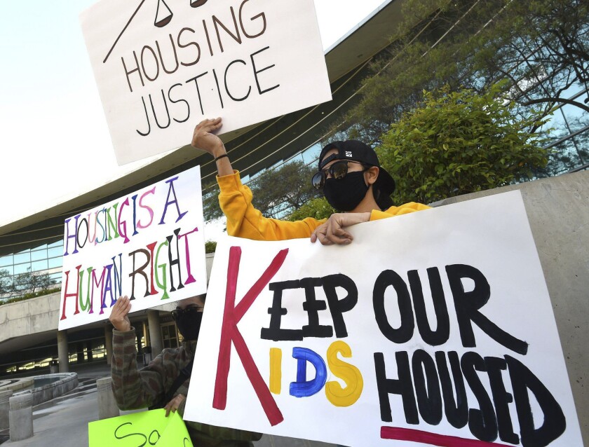 Manifestantes sostienen pancartas durante una conferencia de prensa en el Ayuntamiento de Fresno