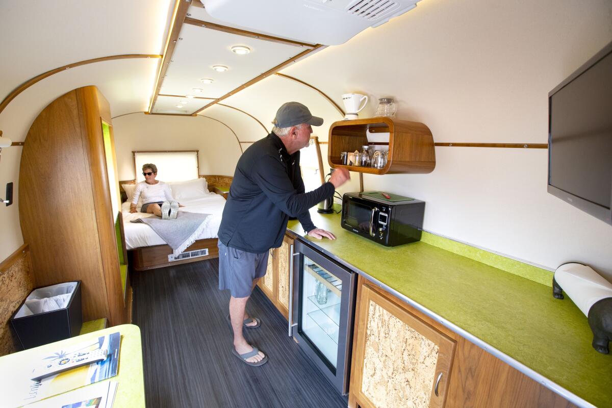 Two people check out the interior of a vintage trailer