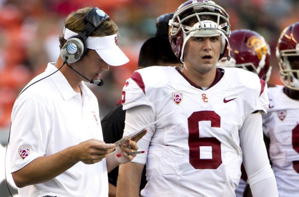 USC Coach Lane Kiffin looks over his list of plays next to quarterback Cody Kessler during the season-opening game in Hawaii.