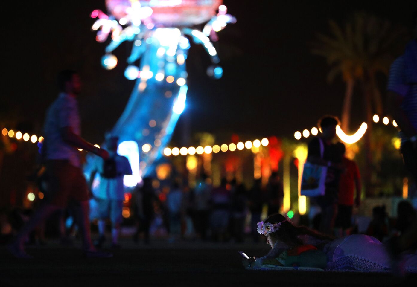 A fan relaxes on the lawn with her smartphone during Beyonce's performance at Coachella.