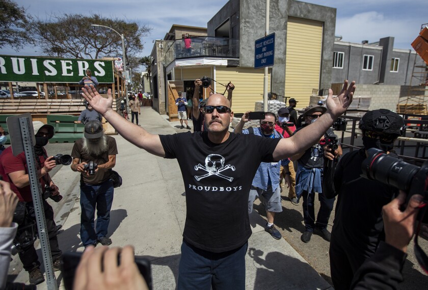 A man wears a Proudboys shirt as a crowd surrounds him in Huntington Beach on Sunday, April 11. 