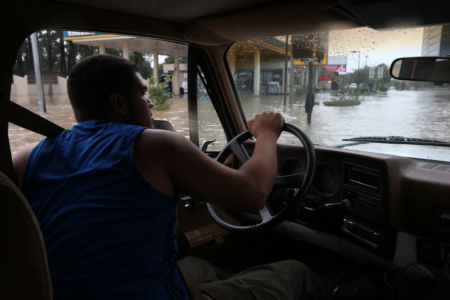 Eduardo Retiz, 21, drives his elevated pickup truck through a flooded street near Addicks Reservoir.