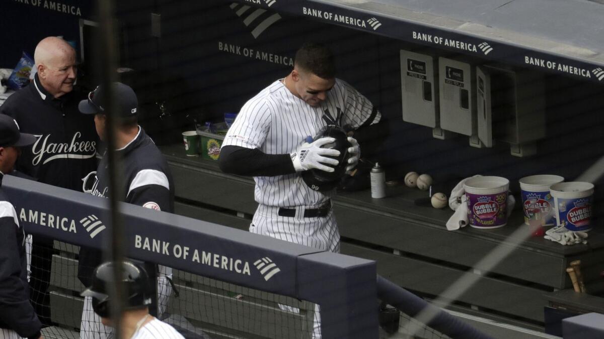 Yankees outfielder Aaron Judge, center, clenches his helmet while walking in the dugout after suffering an oblique muscle strain against the Royals on Saturday.