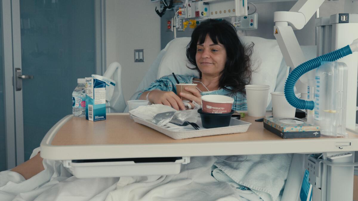 A woman smiles in a hospital bed.