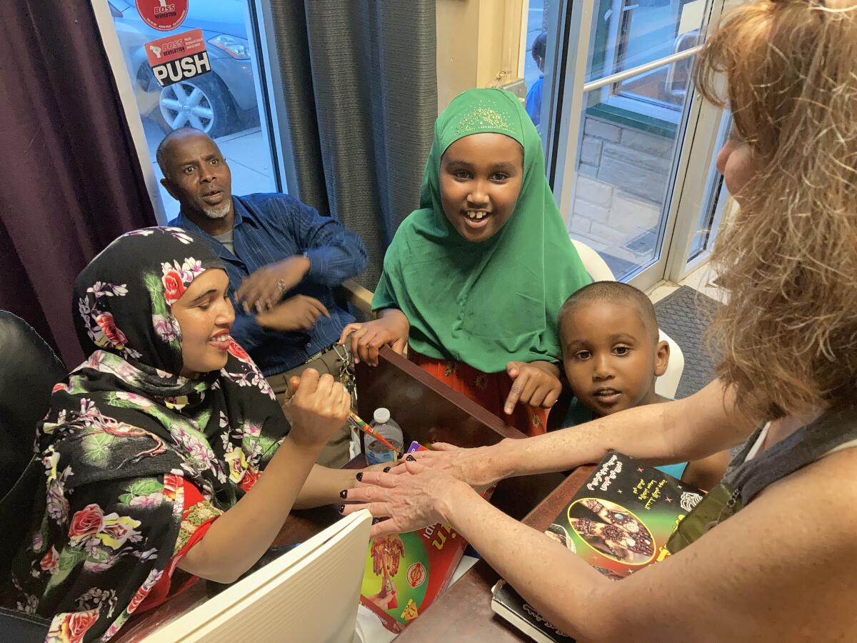 Mushtak Bireh and her brother, Musab, watch their mother Foos give a henna manicure in Postville, Iowa.