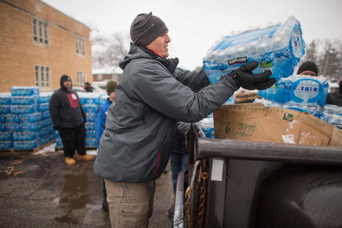 Volunteers load cases of bottled water into vehicles for delivery to residents of Flint, Mich., in March.