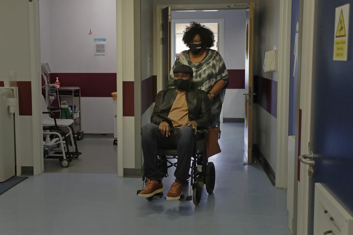 A woman pushing her husband's wheelchair in a hospital