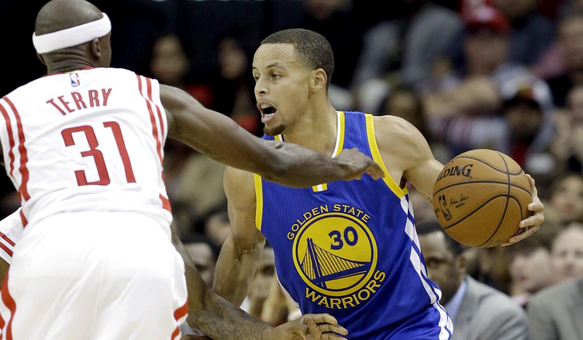 Warriors point guard Stephen Curry faces a double-team defense from guard Jason Terry and a Rockets teammate in the second half Saturday.
