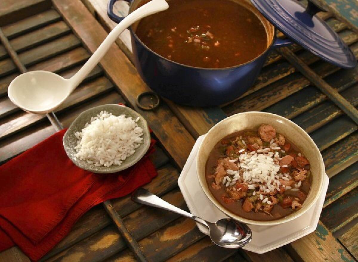 Chicken and andouille smoked sausage gumbo is served over cooked white rice .