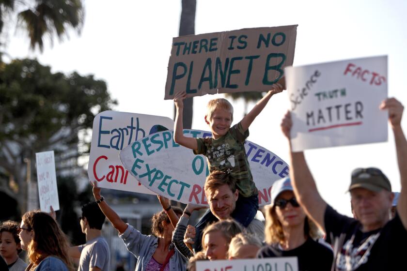 Cedar Reckas, 7 of Laguna Beach, on his dad Ted Reckas' shoulders, holds a protest sign during the Climate Strike climate change protest, at Main Beach Park in Laguna Beach on Friday, Sept. 20, 2019. People throughout the world came out today to protest against climate change.