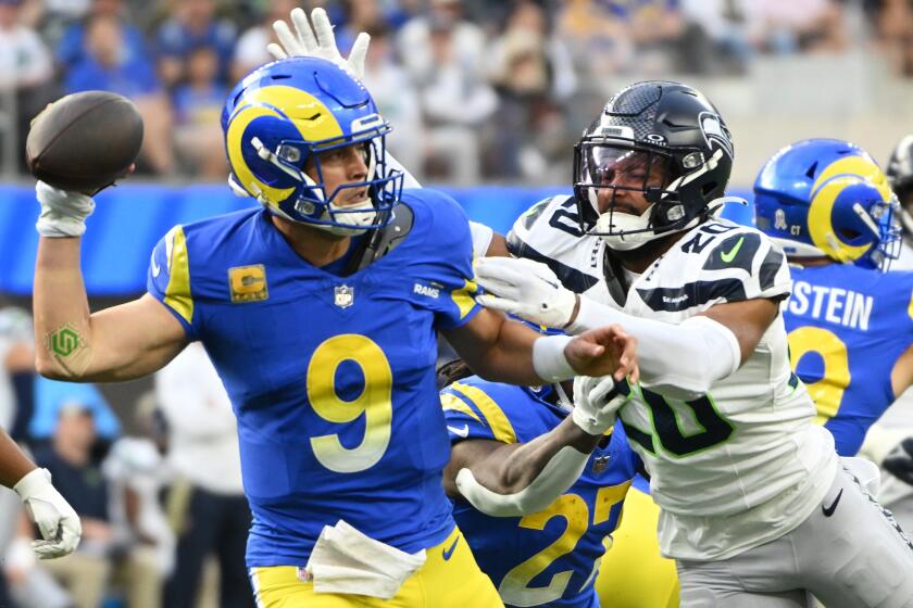 Rams' Matthew Stafford is pressured by Seattle Seahawks' Julian Love.