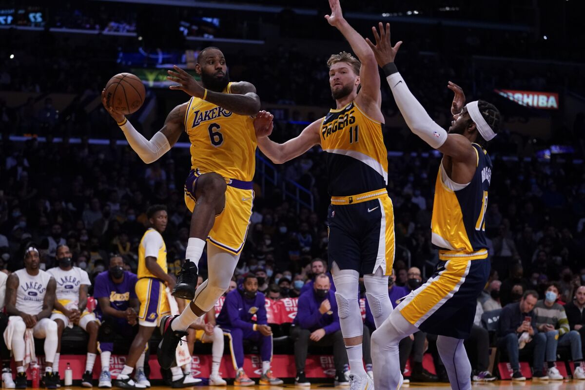 Los Angeles Lakers forward LeBron James (6) passes against Indiana Pacers forward Domantas Sabonis (11) and forward Oshae Brissett (12) during the first half of an NBA basketball game in Los Angeles, Wednesday, Jan. 19, 2022. (AP Photo/Ashley Landis)
