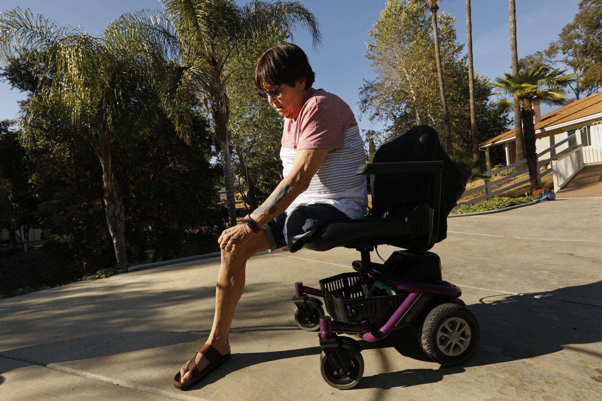 A woman whose leg has been amputated sits on a motorized wheelchair outdoors
