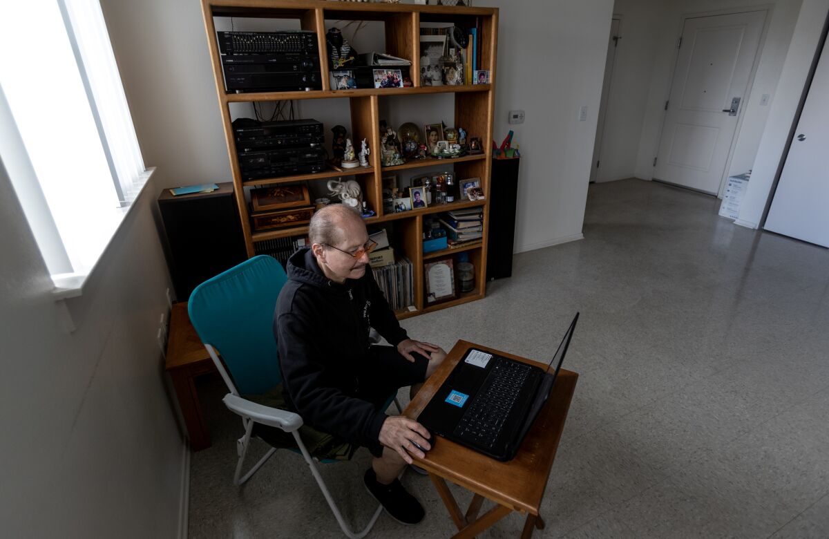 Henry Argueta sits at his computer in his apartment. 