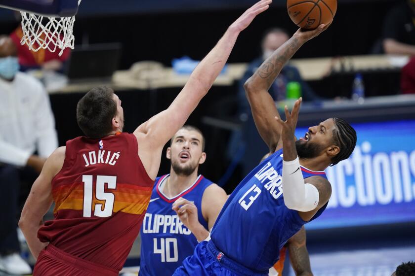 Los Angeles Clippers guard Paul George shoots as Denver Nuggets center Nikola Jokic.