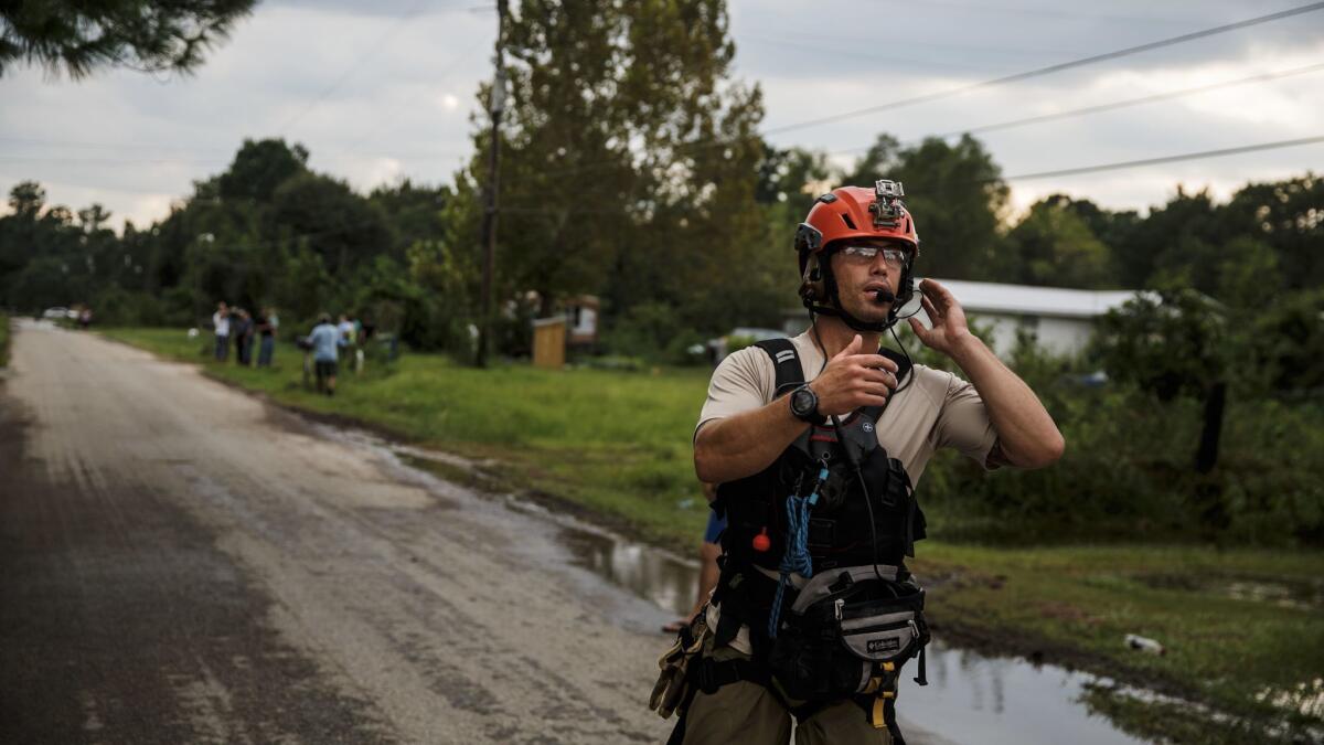 Master Sgt. Adam Vanhaaster signals to his crew as he follows up on an evacuation call in a neighborhood surrounded by floodwater in Orange, Texas.