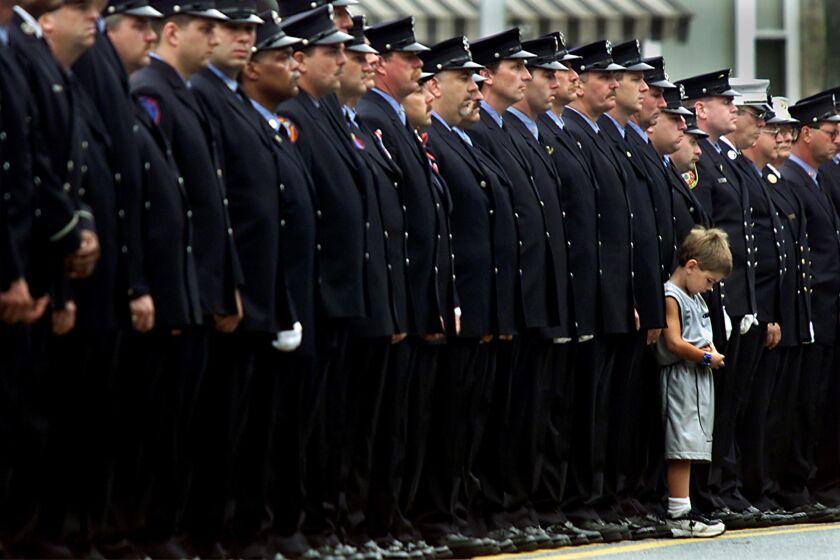 Robert McCann,4, stands with his father Robert during a funeral for fellow firefighter Captain Timothy Stackpole in Brooklyn Monday. Stackpole was killed in the World Trade Center disaster.