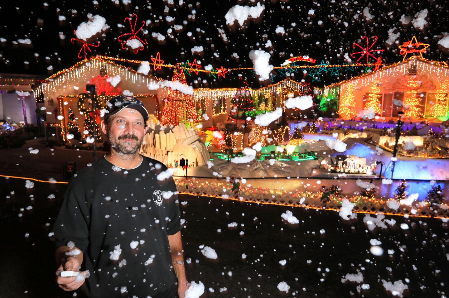 Mack Schreiber uses the remote control of a snow machine to rain down snowy looking soap bubbles at his Christmas decorated home on Reche Road in Fallbrook.