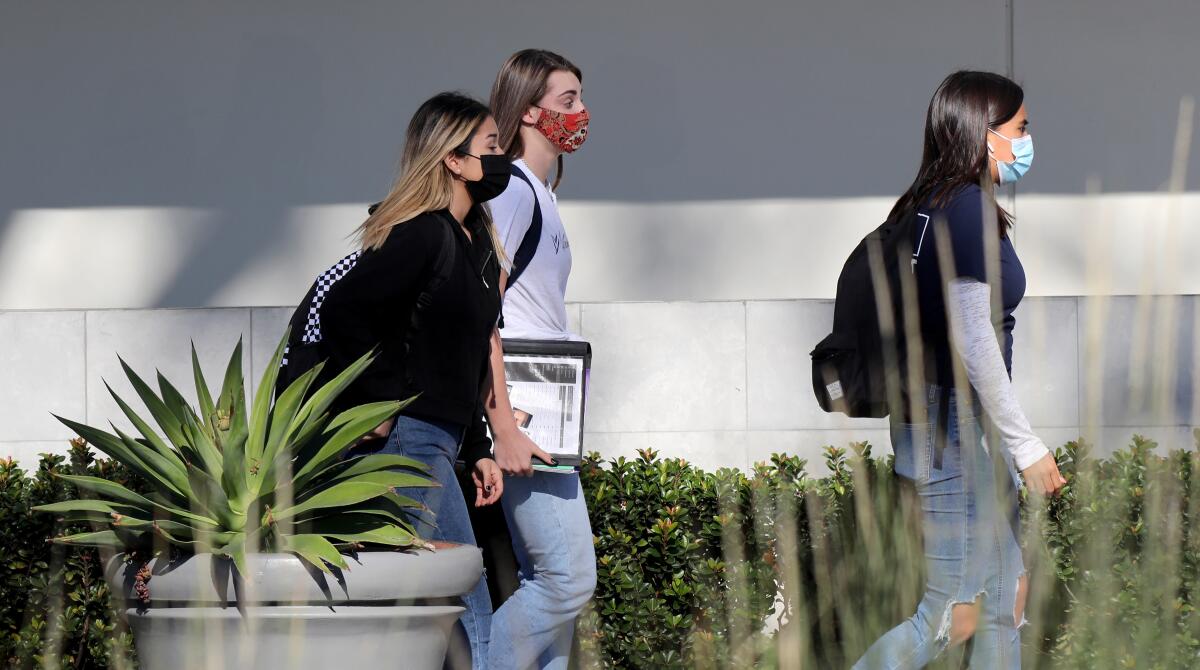 Students wear facial masks on the 1100 block of Irvine Ave. as they walk towards a row of restaurants.