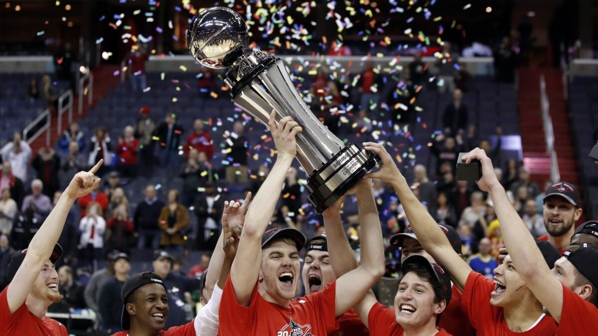 Davidson forward Peyton Aldridge, center, holds the trophy with his teammates after winning the Atlantic 10 conference tournament last March.