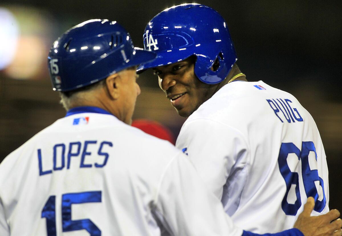 Dodgers right fielder Yasiel Puig gets a pat from first base coach Davey Lopes after driving in a run against the Phillies in the fifth inning, his first of two RBI Wednesday night.