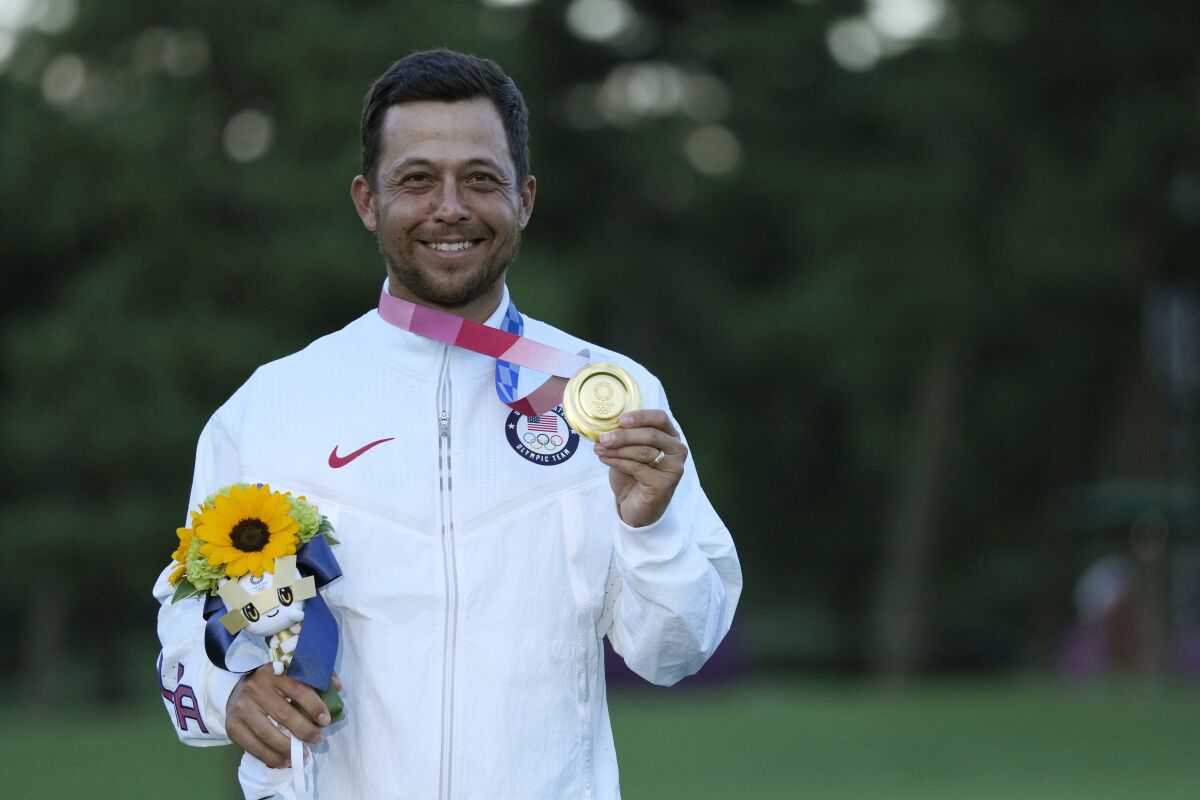 Xander Schauffele holds up his gold medal after winning the men's golf tournament.
